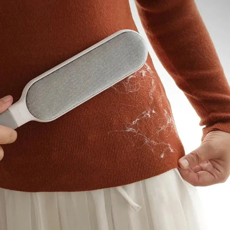 Double-sided pet hair remover brush lifting fur from a sweater